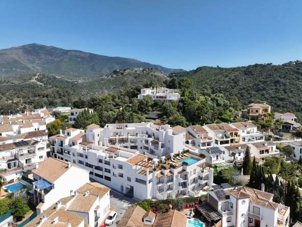 White Mediterranean-style apartment complex with private terraces surrounded by hills in Benahavís, Spain