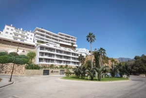 A modern apartment building with white exterior and palm trees in Marbella.