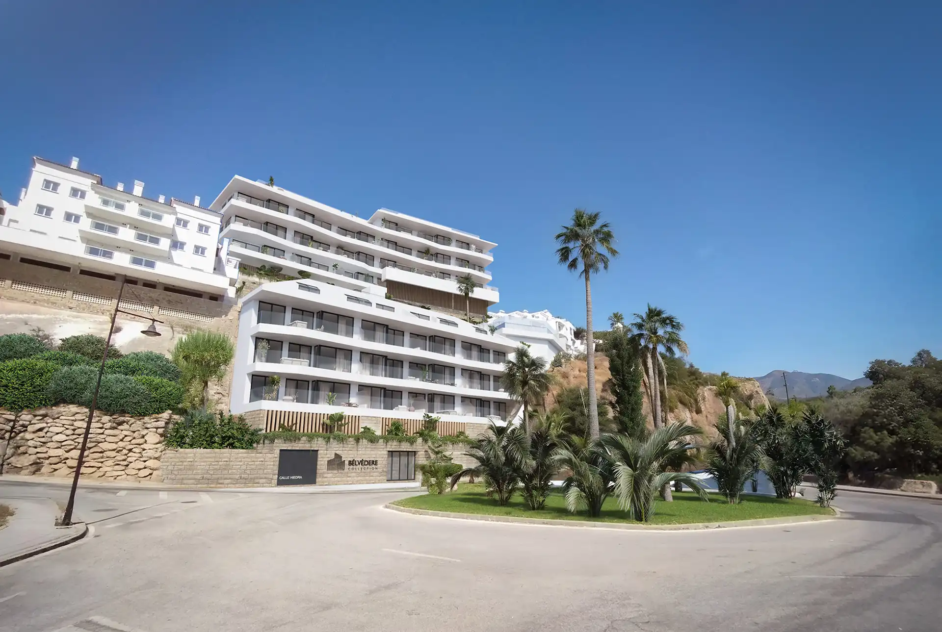 A modern apartment building with white exterior and palm trees in Marbella.