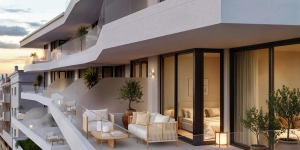 A modern balcony featuring outdoor furniture, plants, and glass railings.