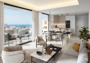 Interior view of a modern living room and kitchen with large windows showing a sea view.