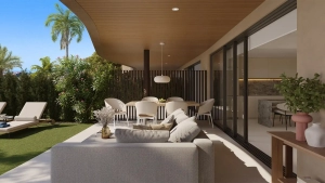 A modern outdoor living area featuring a sofa, dining table, and greenery.