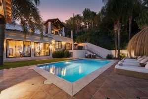 Exterior view of Villa Las Palmeras in Benahavis featuring a swimming pool and palm trees.