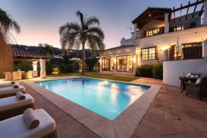 A villa with a swimming pool and palm trees in Benahavis during twilight.