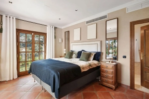 A well-furnished bedroom featuring a bed with decorative pillows and a wooden nightstand. Villa Las Palmeras Benahavis,