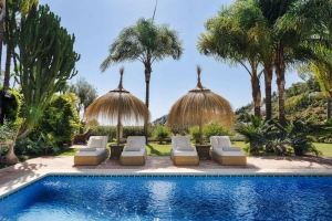 Outdoor area of Villa Las Palmeras featuring a swimming pool and thatched umbrellas.
