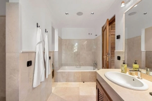 Modern bathroom featuring a bathtub, sink, and towels hanging on hooks.