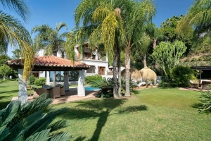 Exterior view of Villa Las Palmeras in Benahavis with palm trees and garden.