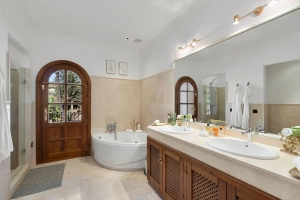 Modern bathroom featuring a bathtub, double sink, and wooden door.