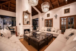 A spacious living room featuring white sofas, a glass coffee table, and decorative lighting fixtures.