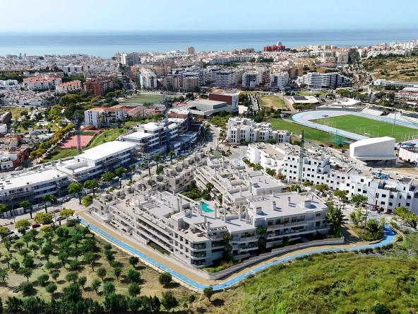 Aerial view of Anna de Estepona New Development showing buildings, greenery, and the coastline in the background.
