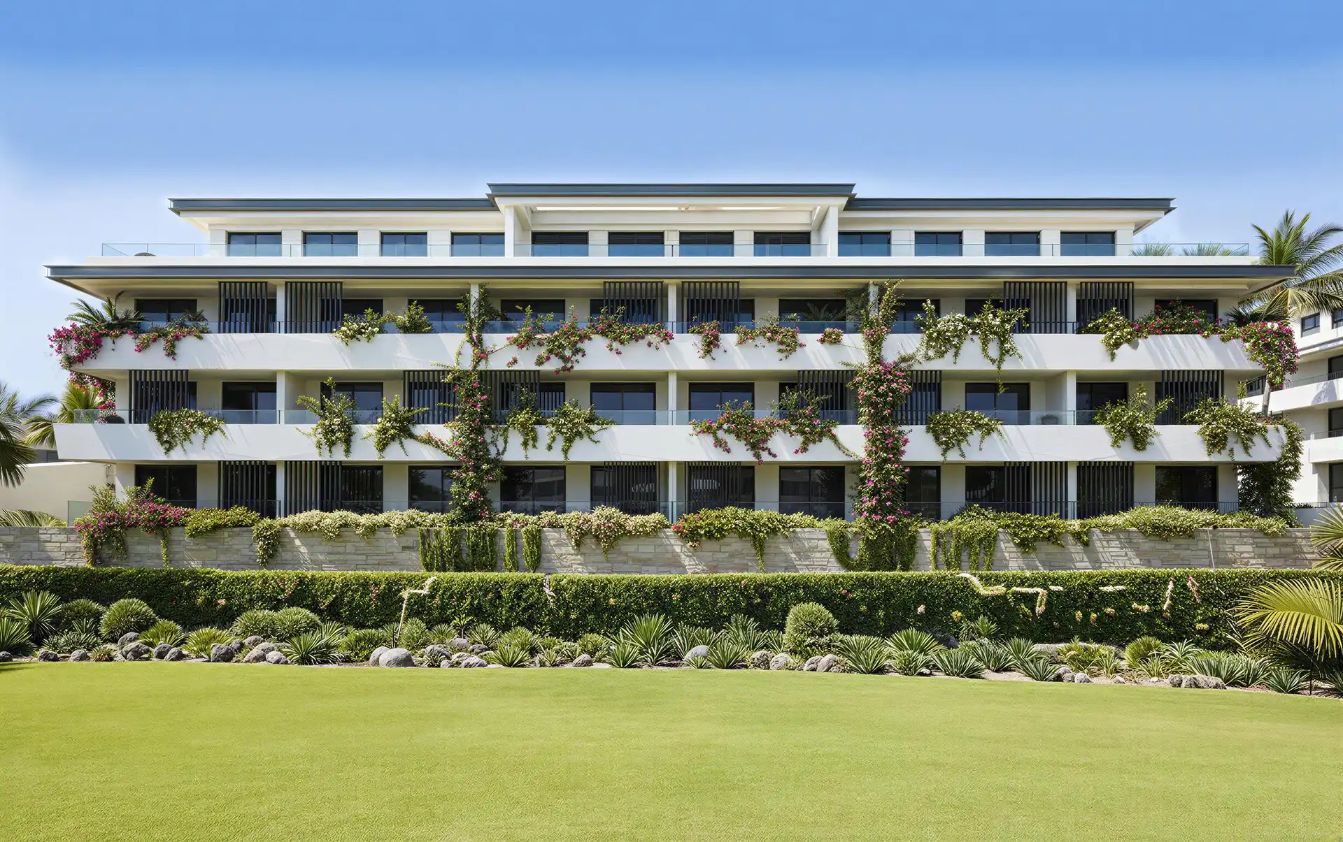 Senora Gardens Mijas Edificio de apartamentos contemporáneo blanco de tres pisos con amplios balcones adornados con buganvillas en cascada y plantas tropicales.