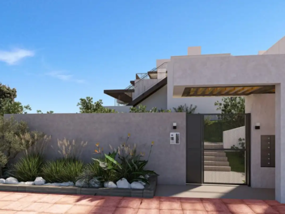 Contemporary villa entrance featuring gray stucco walls, metal gate, and drought-resistant landscaping under blue sky