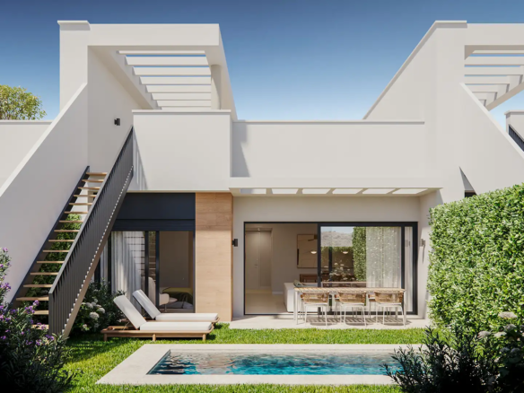 Contemporary white villa exterior with small private pool, sun loungers, outdoor dining terrace, and lush green hedging under blue sky