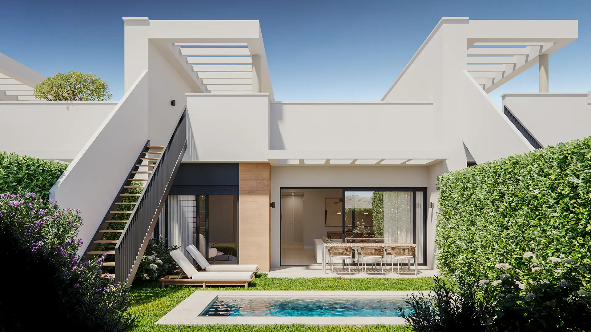 Contemporary white villa exterior with small private pool, sun loungers, outdoor dining terrace, and lush green hedging under blue sky