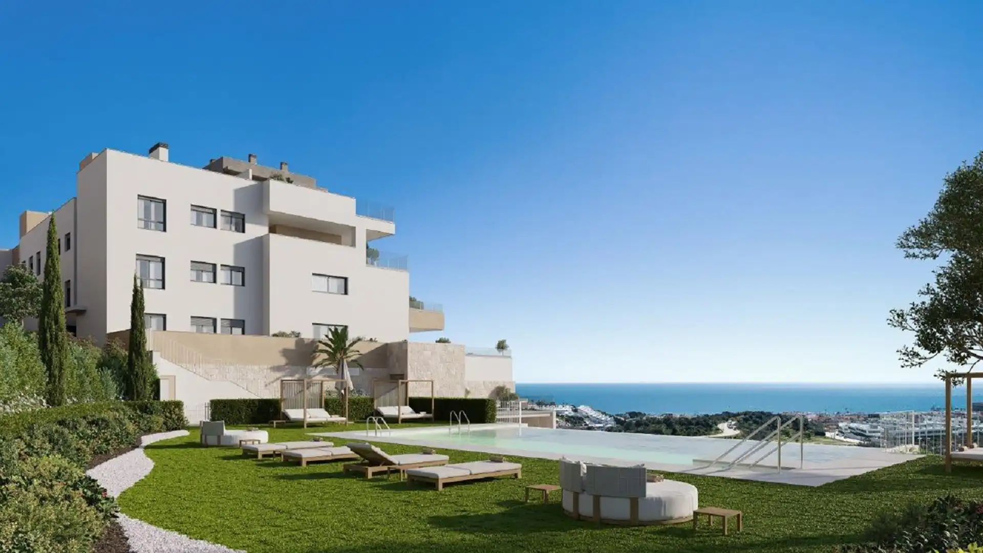 Modern white luxury apartment complex with infinity pool, sun loungers, manicured lawn, and panoramic Mediterranean sea views