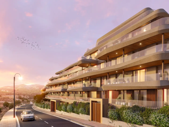 Modern terraced apartment complex at Vission Hills Mijas with curved balconies, glass railings, and mountain views at golden hour