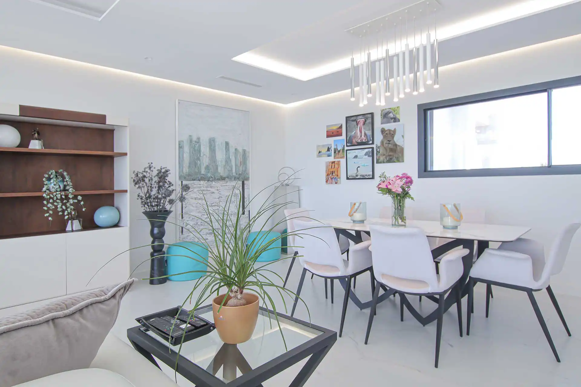Bright modern dining room with white chairs, marble table, pendant lighting, and gallery wall at Lotus Dona Julia