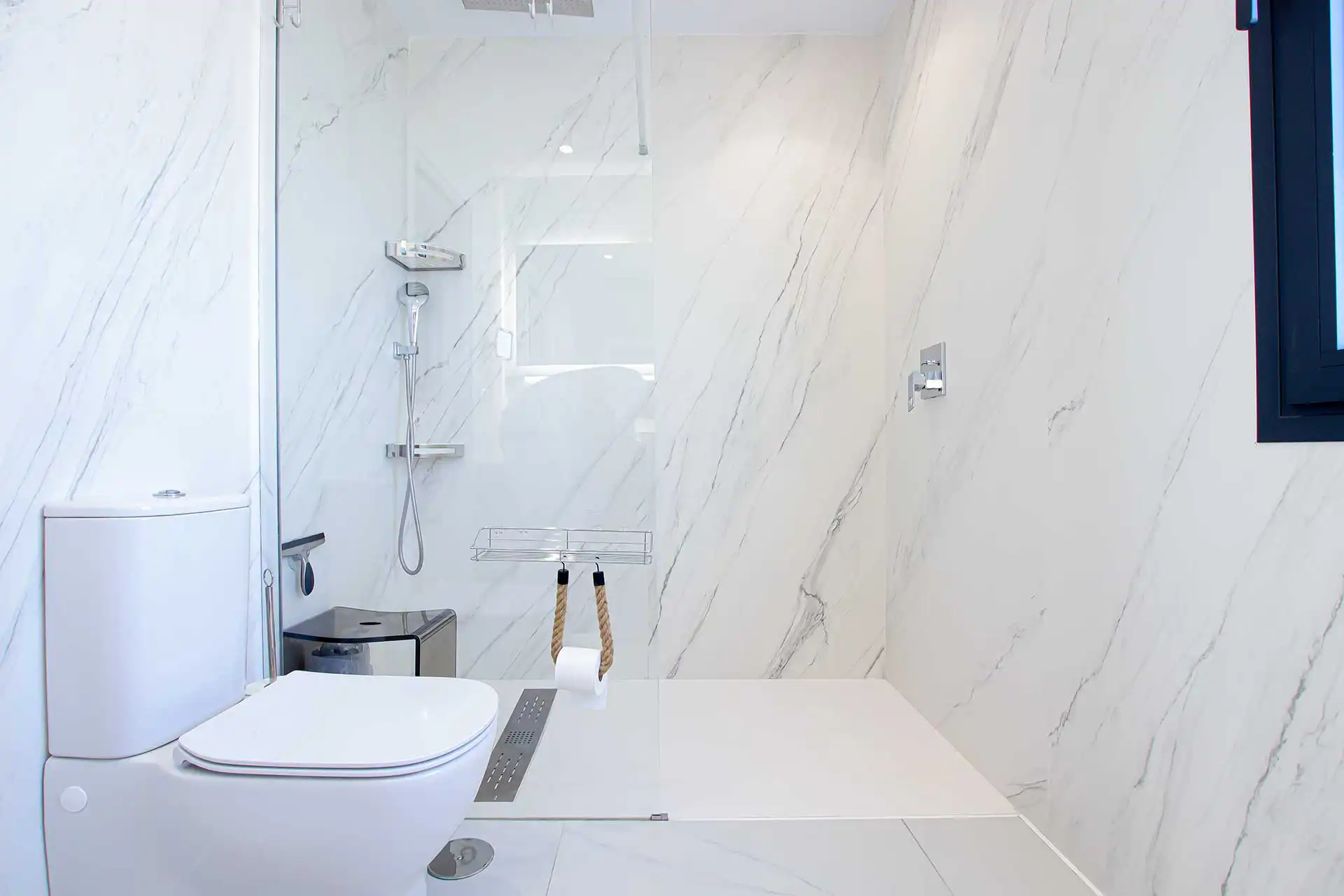 Modern white marble bathroom with walk-in shower, rainfall head, and sleek toilet at Lotus Dona Julia property
