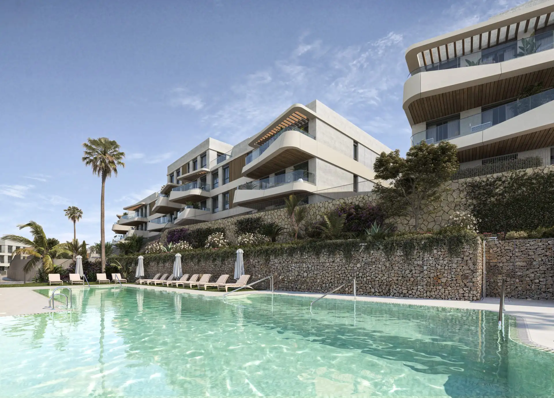 Terraced apartments with pool, stone retaining walls and gardens on a hillside in West Estepona